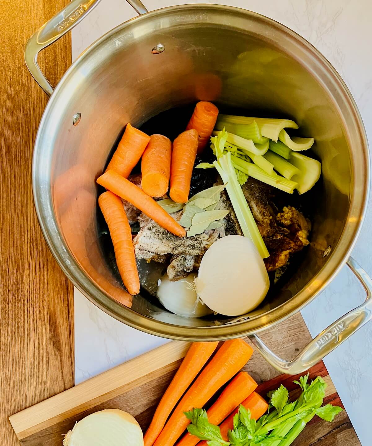 stockpot with chopped vegetables chicken and seasoning on a wooden board