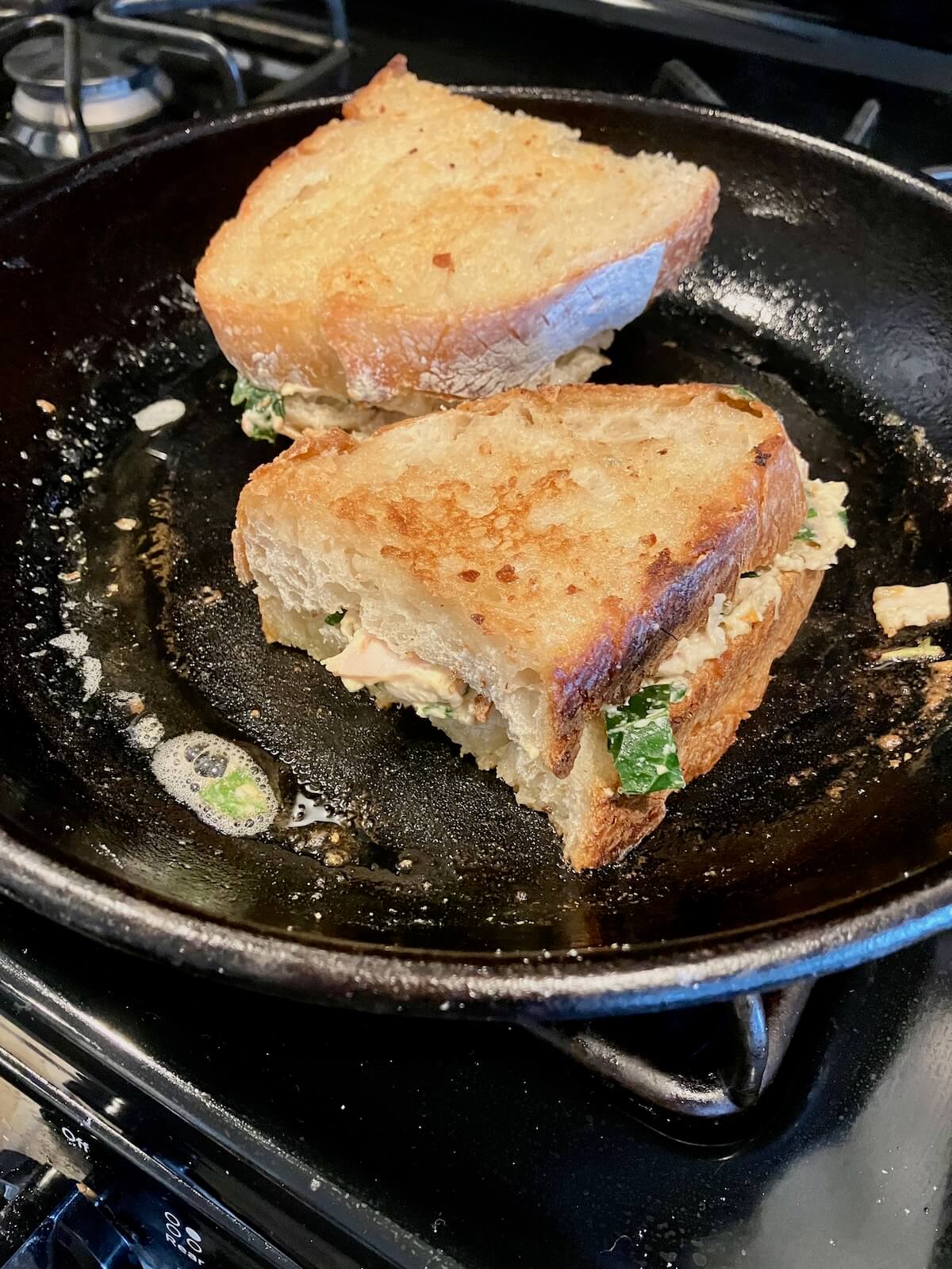 grilled cheese cooking in cast iron pan on the stovetop