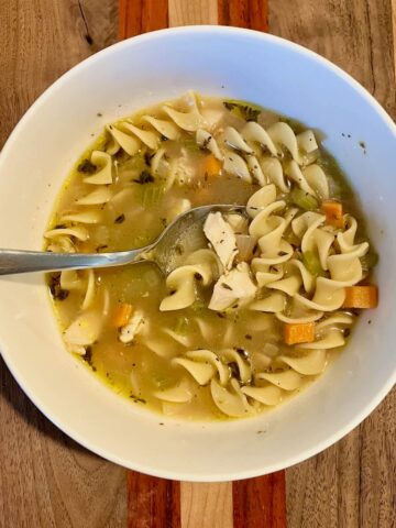 bowl of chicken noodle soup on a wooden board