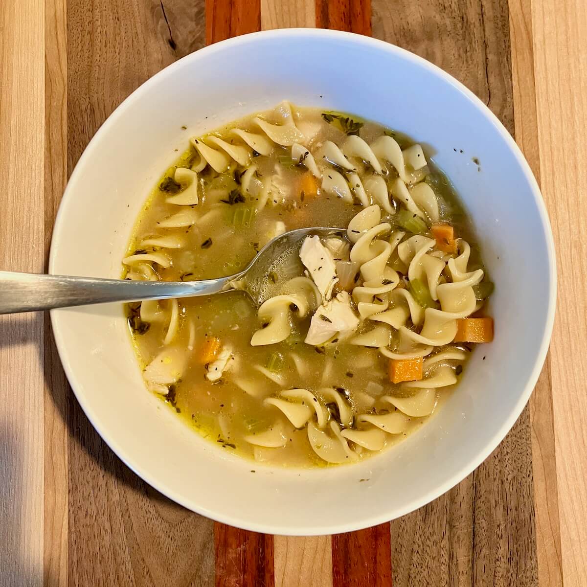 bowl of chicken noodle soup on a wooden board