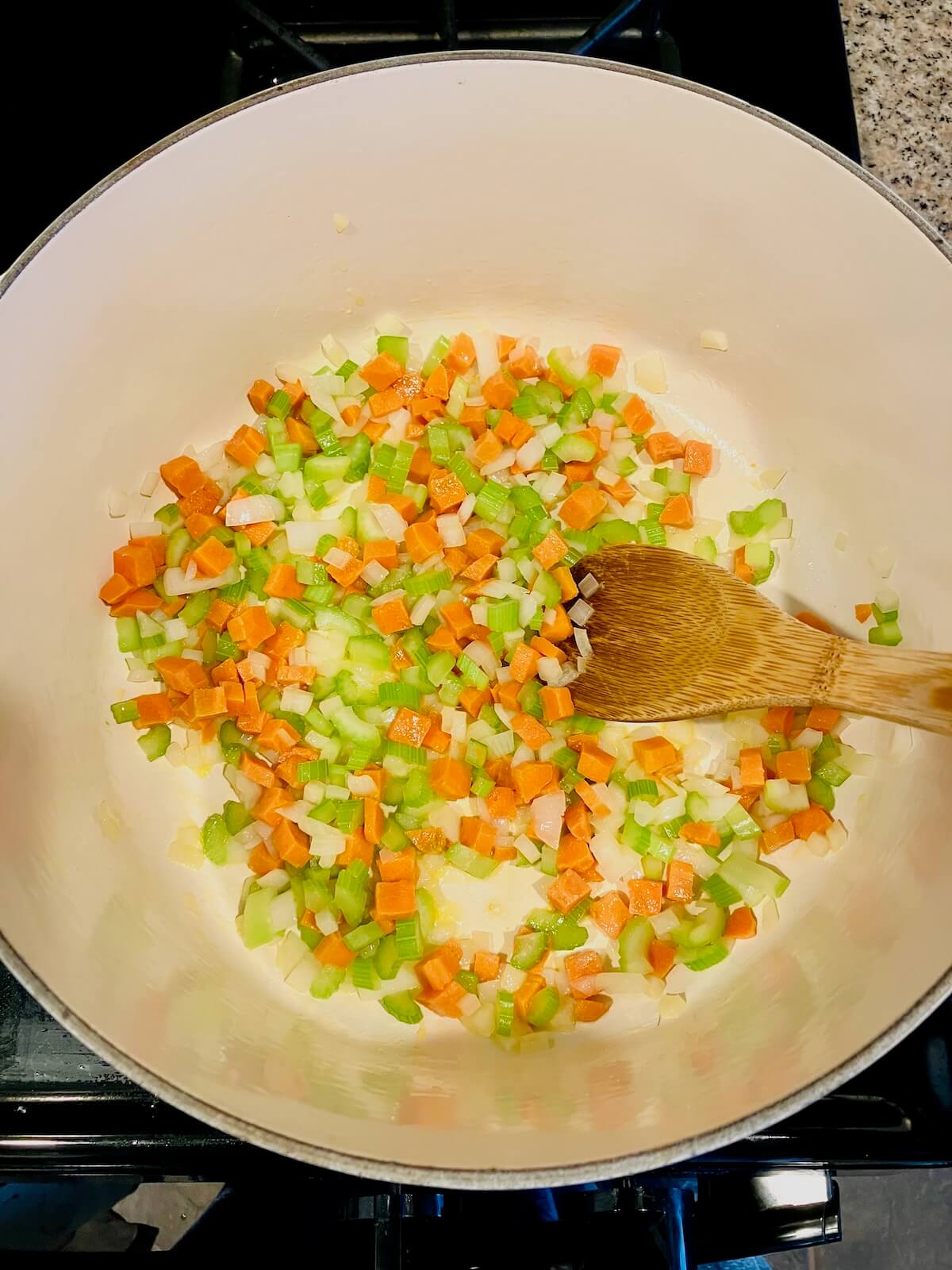 carrot celery and onion cooking in a white pot