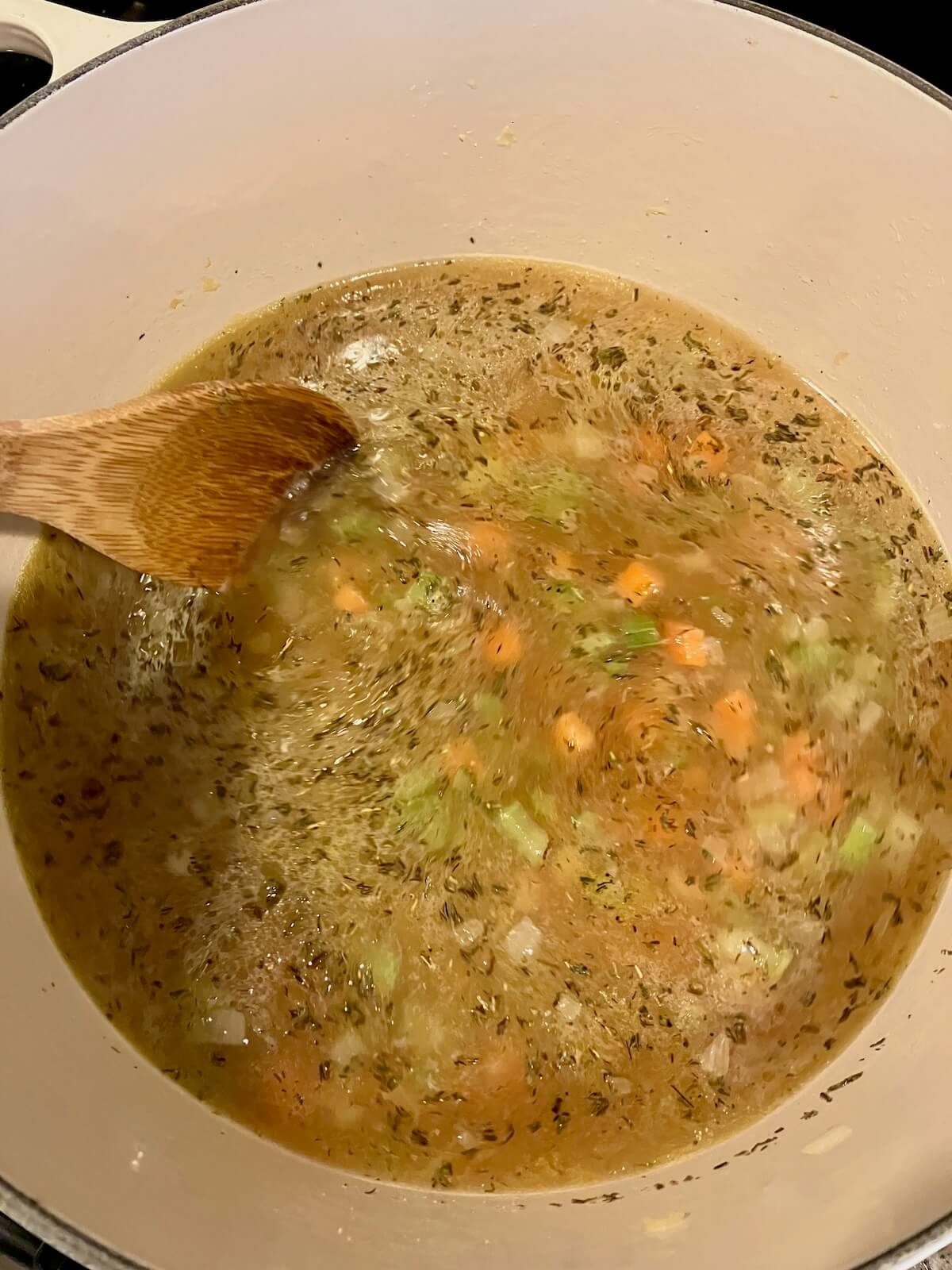 chopped vegetables cooking in a pot of chicken broth