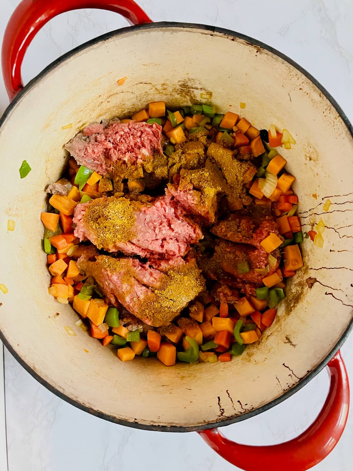 chopped vegetables and ground beef cooking in a pot