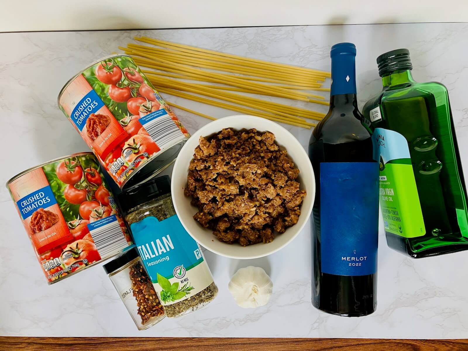 ingredients for merlot pasta sauce including tomato seasoning italian sausage garlic pasta merlot and olive oil