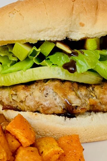 close up of pork apple burger with sweet potato on the side