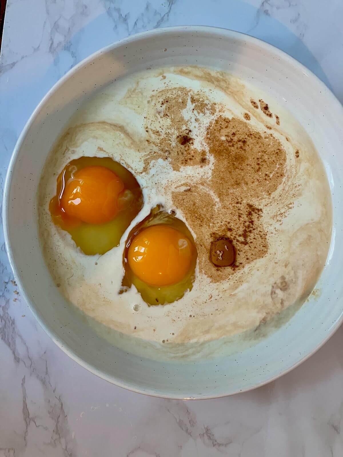 eggs custard ingredients in a white bowl on a white background