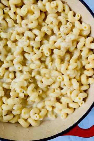 mac and cheese in a red enameled cast iron pot on a marbles background