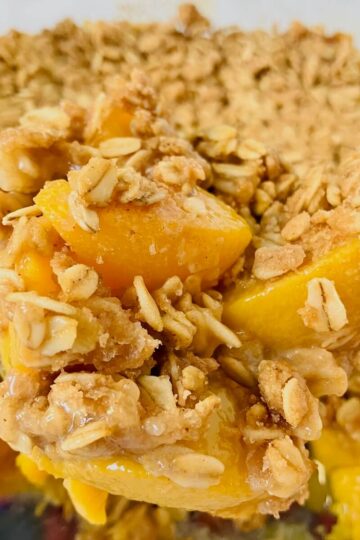 close up of peach crumble with peaches showing through oat topping