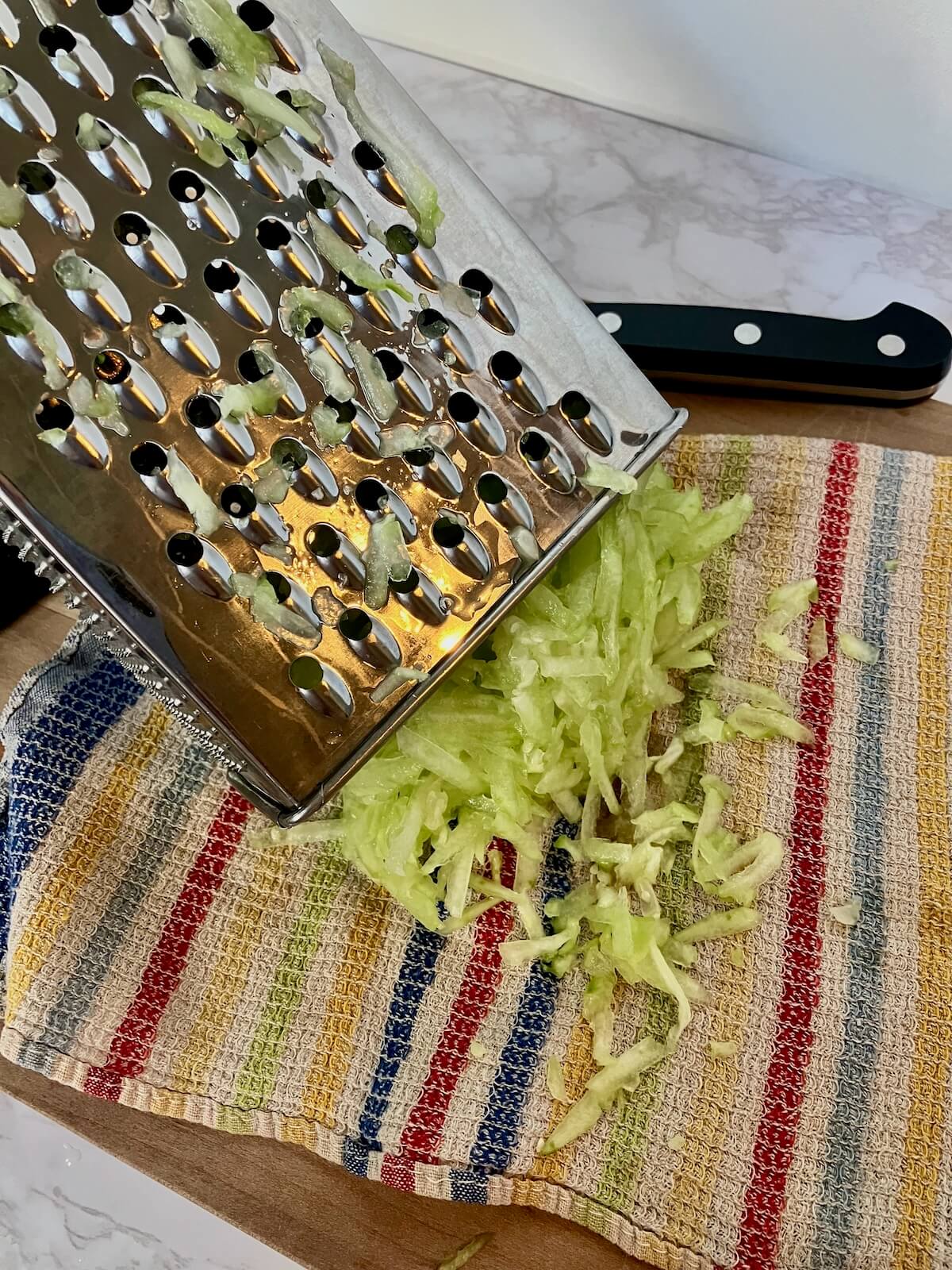 box grater with cucumber on a towel
