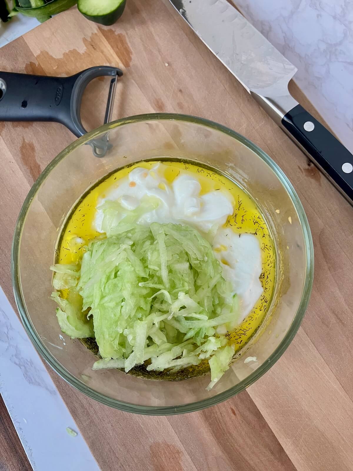 grated cucumber in a bowl on a cutting board