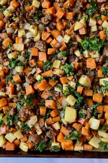 sausage, apple, sweet potato, kale and onion on a baking sheet
