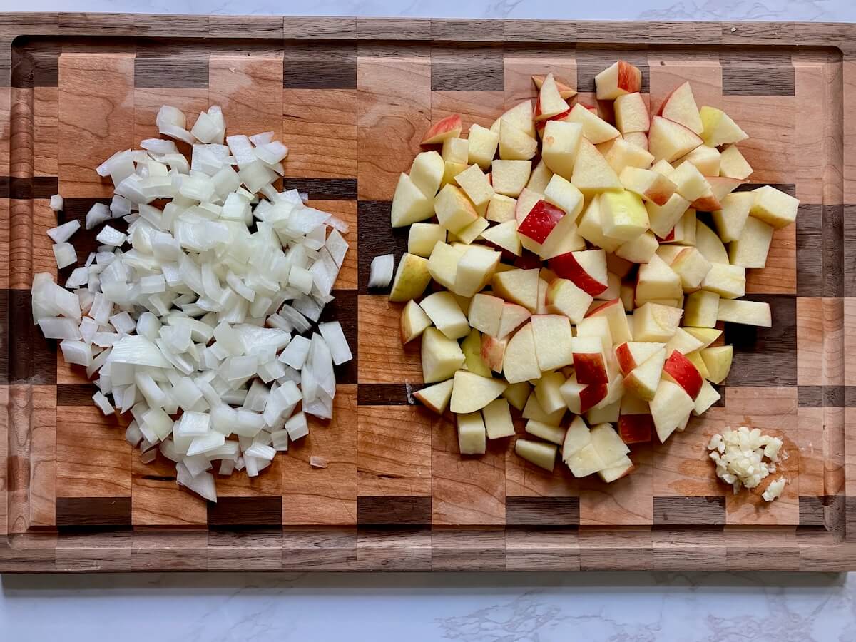 apples, onions and garlic diced on a wooden cutting board