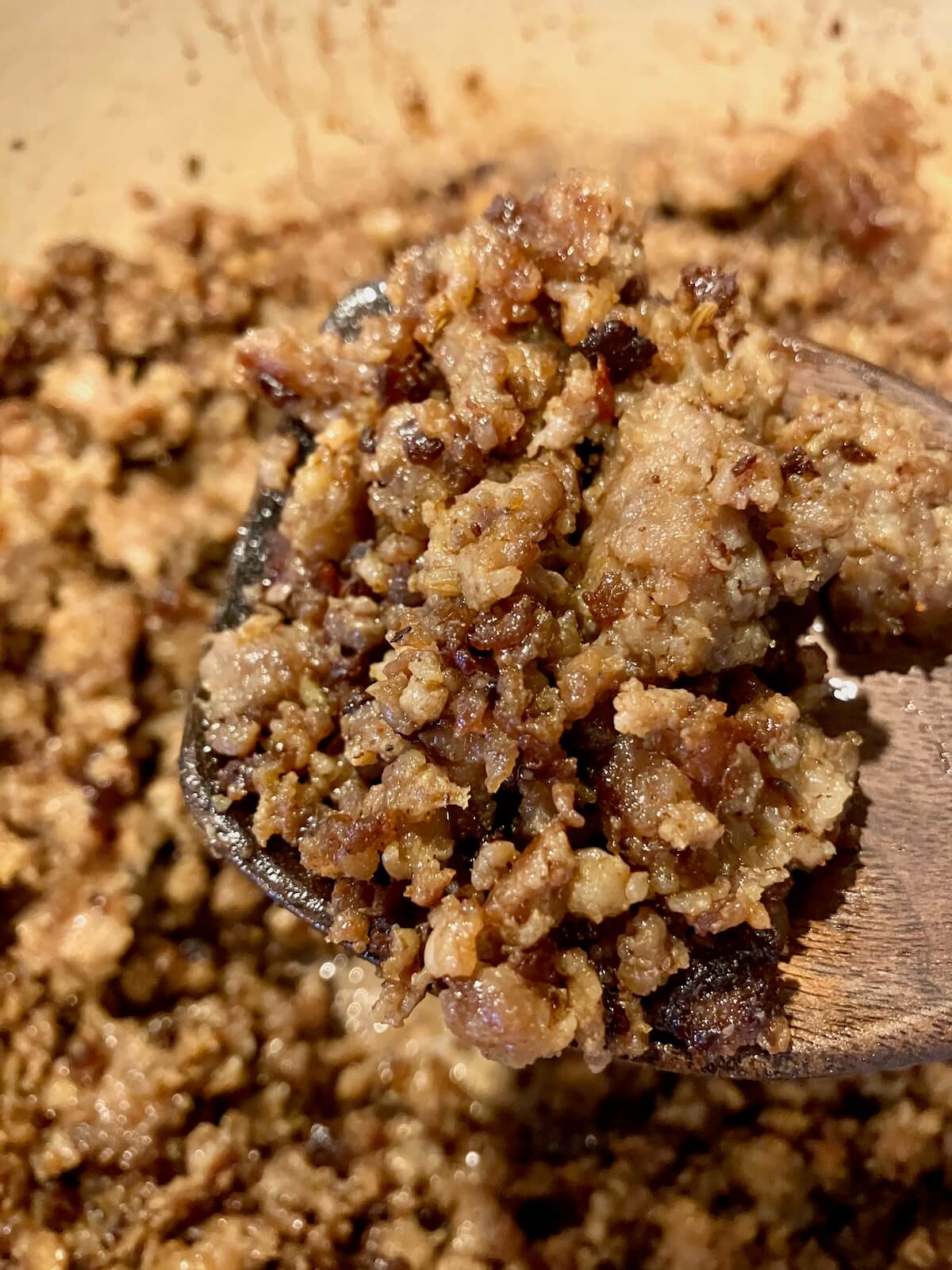close up of cooked Italian sausage on a wooden spoon