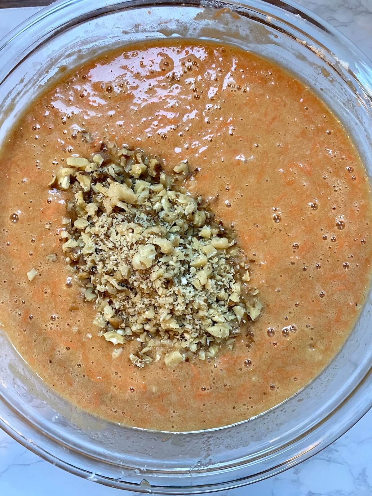 carrot cake cupcake batter with walnuts on top