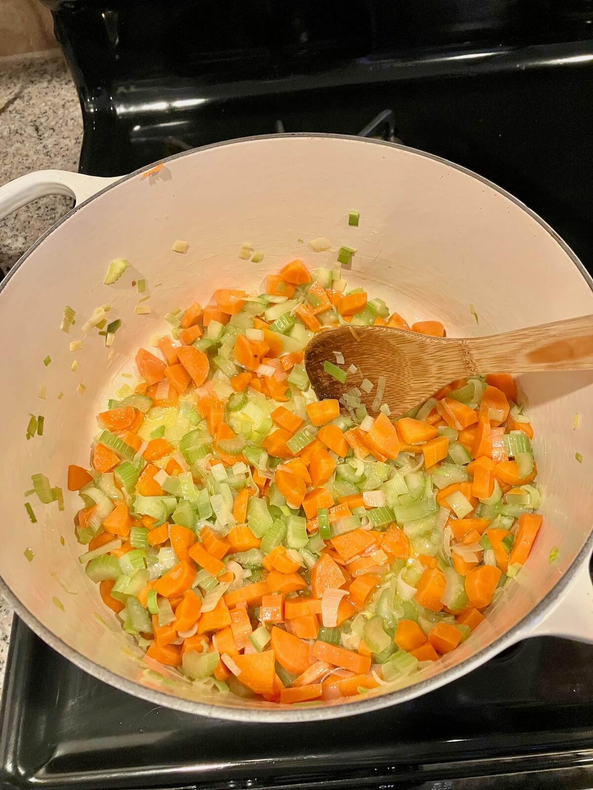 carrots celery leeks and onions in a white dutch oven